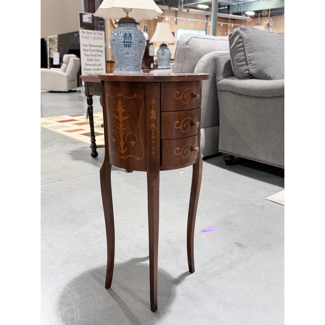 A charming vintage Italian round chest, beautifully adorned with delicate inlaid scrollwork and subtle floral motifs. The...