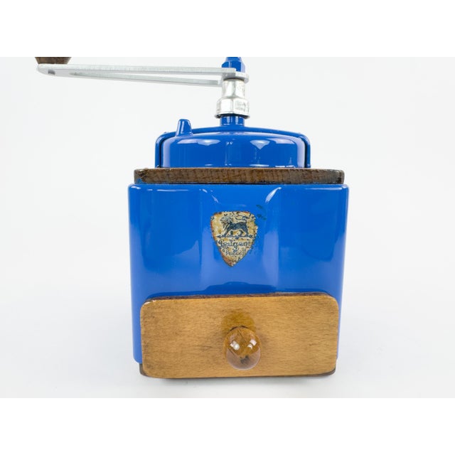 A distinctive vintage French manual coffee grinder by Peugeot Frères, featuring a vibrant cobalt-blue painted metal body...