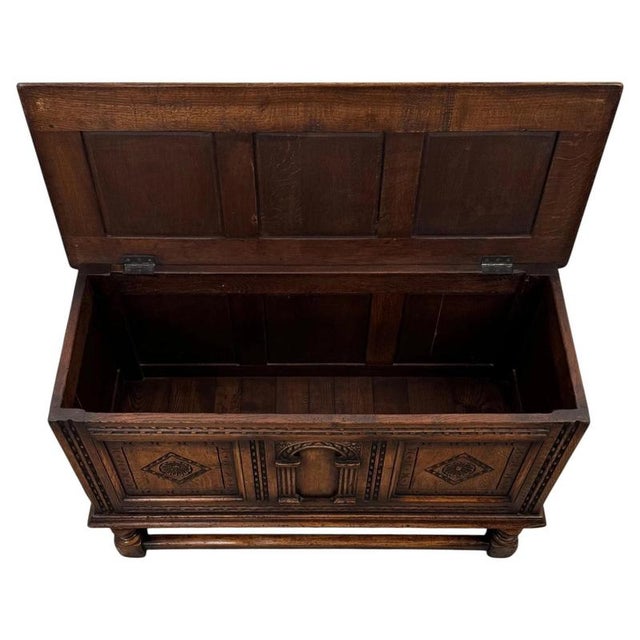 A handsome early 20th-century English blanket box on stand, finely crafted from oak and distinguished by its richly carved...