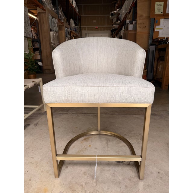 Elevate your dining space with this contemporary counter stool, featuring a softly textured ivory upholstery paired with a...