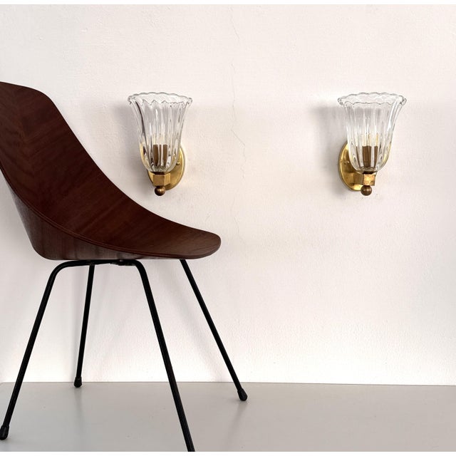 Set of two gorgeous wall lamps made of transparent thick Murano glasses in light wavy shape and sturdy brass wall bracket....