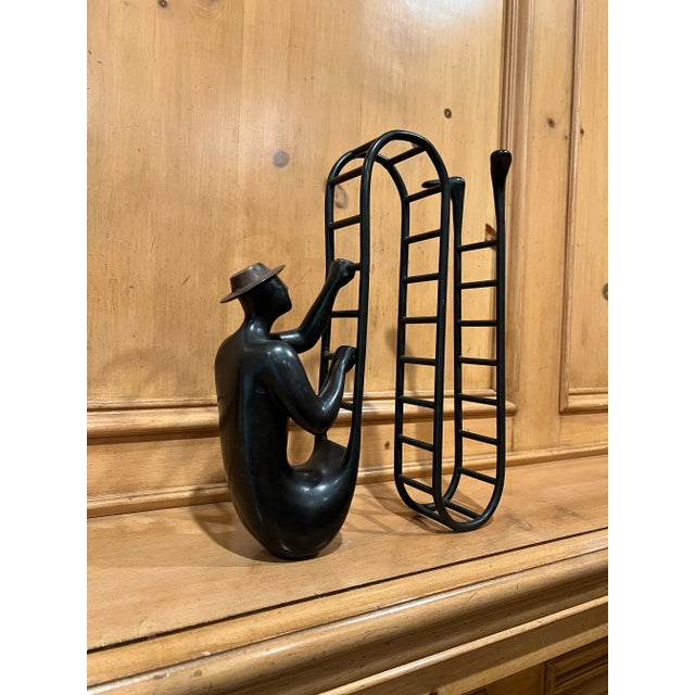 This whimsical sculpture says so much about climbing the ladder of success. Bronze man with a hat climbing a ladder only...