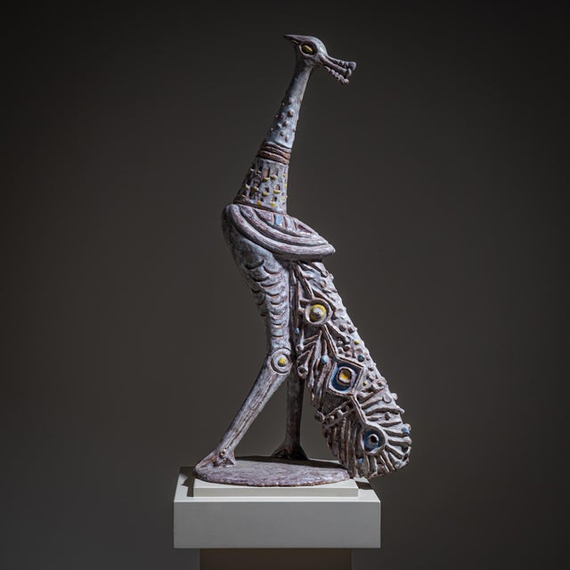 Glazed terracotta figure of a proud peacock with stylized plumage, raised on a circular base. Signed on the underside:...