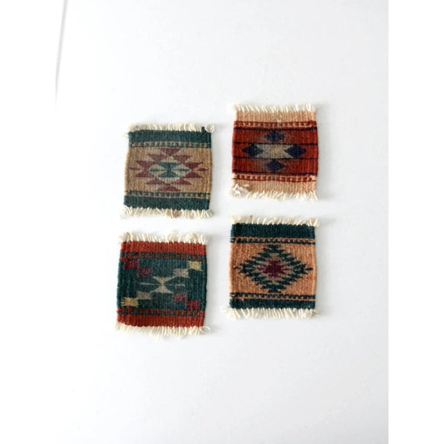 This is a set of four vintage southwestern textile coasters. With varying patterns, the woven wool mats feature fringe...