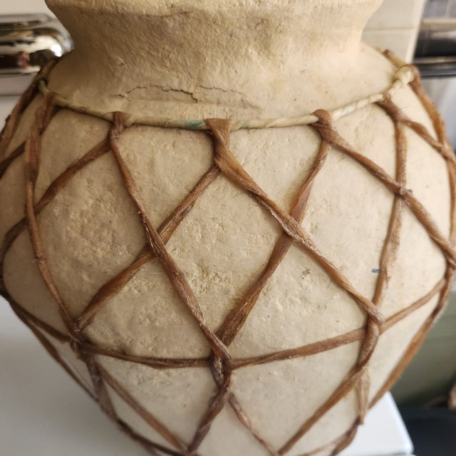 A hand made Papier mache urn. Very decorative with a great nubby texture. The vase is encased in a rawhide basket.