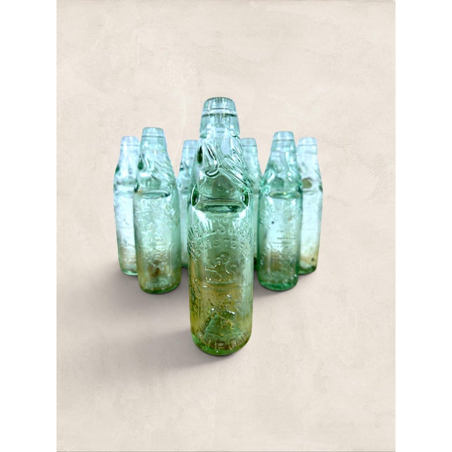 A charming collection of nine antique English aqua glass cod neck bottles from Bristol, dating to circa 1900. Each bottle...