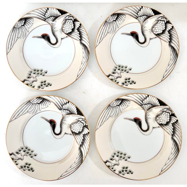 A striking set of four Fitz & Floyd fine porcelain dinner plates in the elegant “Crane With Pine” pattern, produced in...