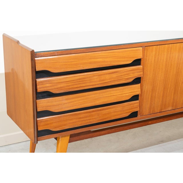 Italian sideboard from the 1950s, made of sapele wood in its natural color and polychrome black. It features an opaque...
