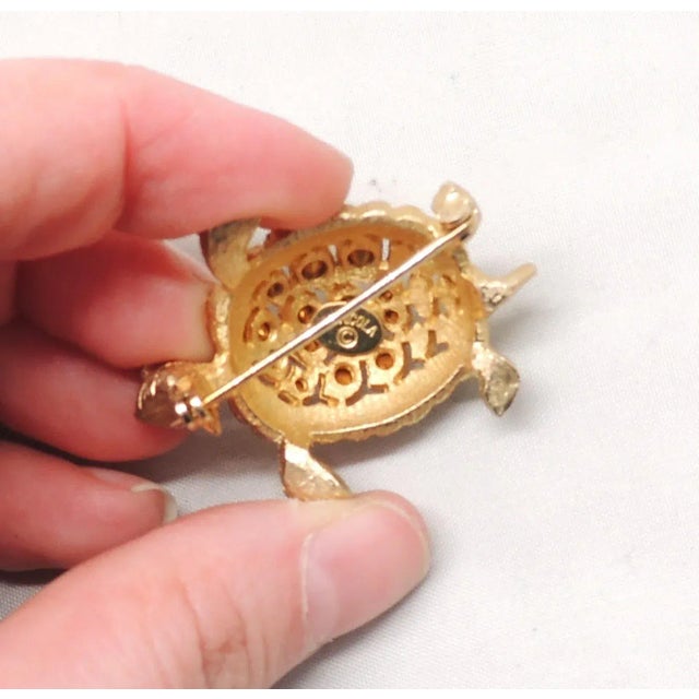 This is part of Chairish’s Costume Jewelry assortment. Circa 1960s goldtone turtle with round faux-peridot eyes and a...