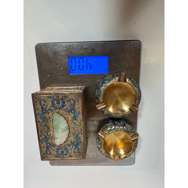 A beautiful early 20th-century Chinese export silver and enamel three-piece smoking set comprising a tabletop cigarette...