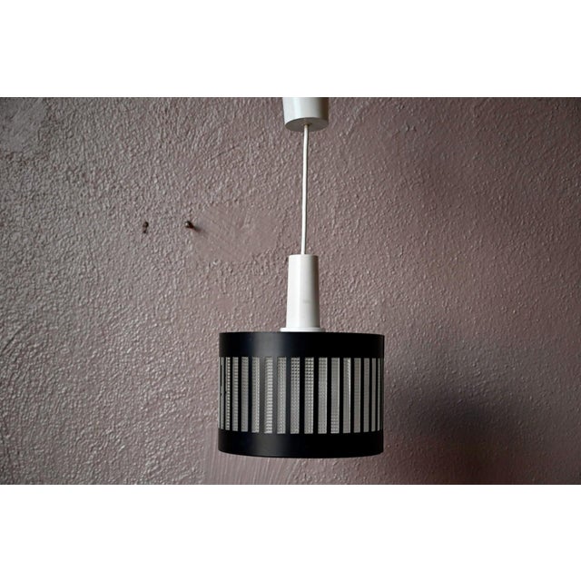 This pendant light, with its clean, modern lines, is a mid-century design. It consists of a black-painted, perforated...