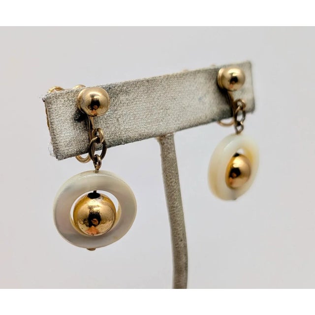 Late 1970s or early 1980s goldtone ball top with cut out circle of mother-of-pearl with a goldtone ball in the center drop...