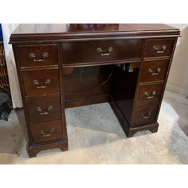 Vintage mahogany kneehole desk features decorative brass bail hardware and multiple drawers on either side. This piece is...