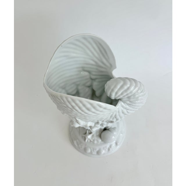 Beautiful porcelain vase in the shape of a nautilus shell with coral branches and smaller shells. Likely a reproduction of...