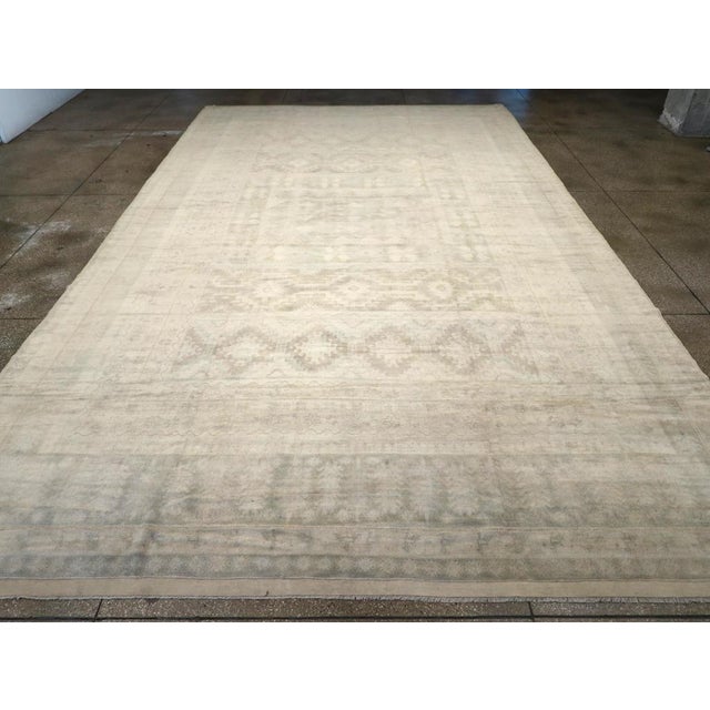 A wool pile of symmetric knots on a cotton foundation. This extra-large Moroccan town piece features a strongly muted...
