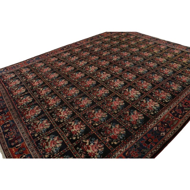 Hand-knotted with wool, originating circa 1920-1930, this 12x15 antique Persian Bakhtiari rug enjoys a rich black field...