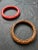 This set includes two molded plastic bangle bracelets in carved floral relief—one in coral pink the other in warm brown....
