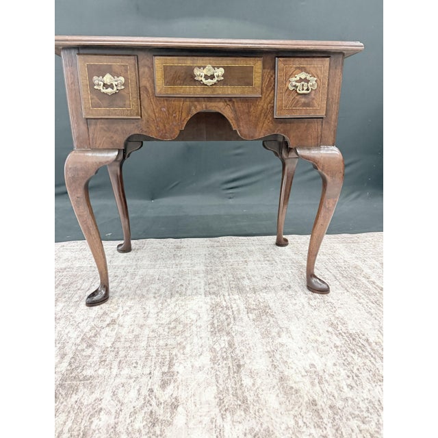 A Councill Craftsmen Queen Anne style lowboy — flame-veneered top with satinwood crossbanding and fan inlay, three drawers...
