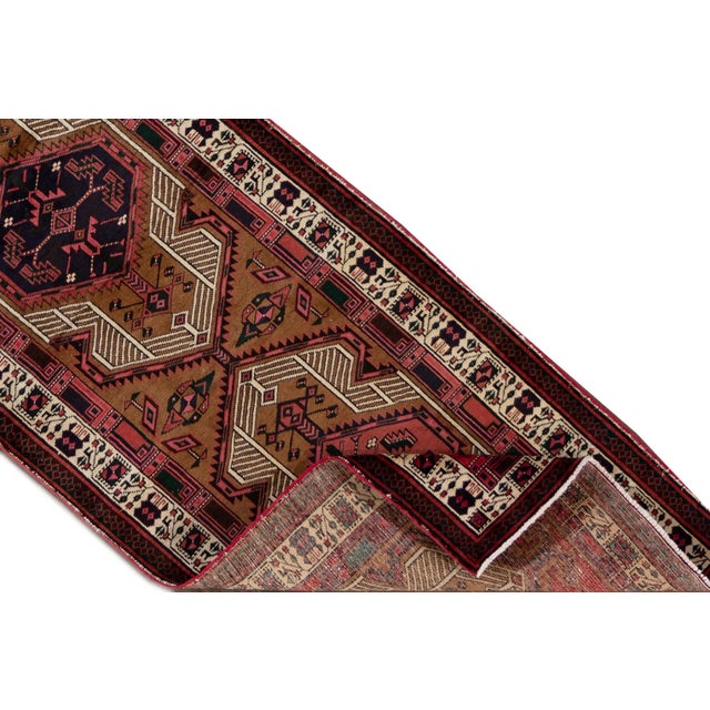 A beautiful Vintage Heriz Handmade Wool Rug with a brown and pink field and multicolor accents in allover geometric...