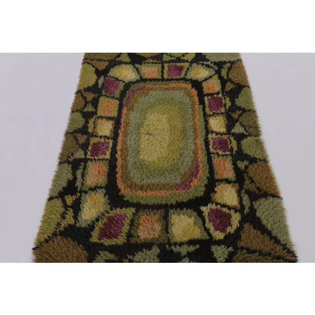 Hand-knotted in lush, high-pile wool in Sweden circa 1960-1970, this 3x6 vintage Swedish Rya runner rug is a bold new...