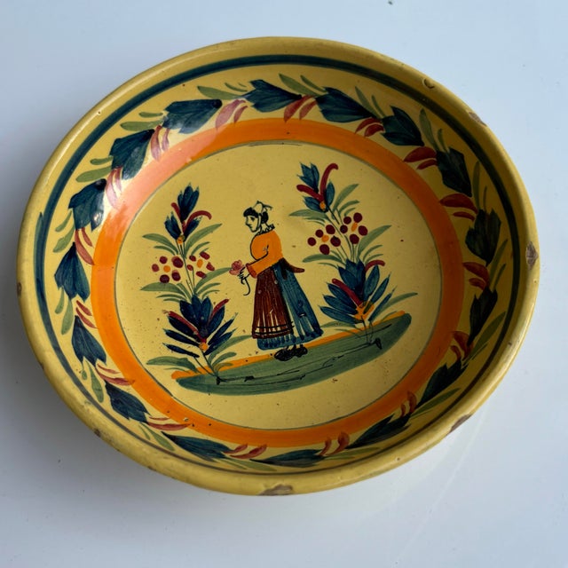 Antique bowl with hand painted design featuring a traditional Breton woman with floral/botanical accents.. Marked "Henriot...