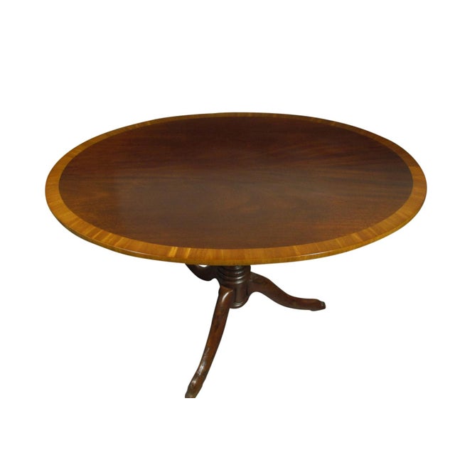 A 19th-C. English inlaid mahogany tea table with satinwood banding, tilt top mechanism and solid hand carved yew wood base.
