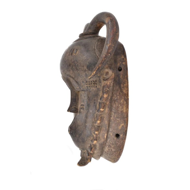 A stunning Yaure Baule Portrait Mask with triangular carved elements around the jaw in the traditional Baule style. This...