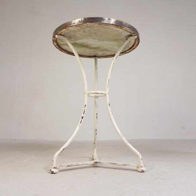 Elegant bistro table from the early 20th century with a robust base and a luxurious marble top. The round marble top rests...