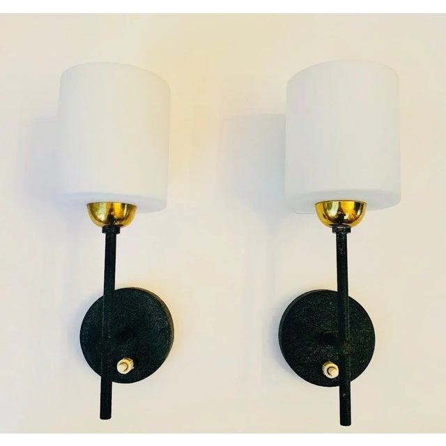 A pair of black enamel and polished brass sconces with white opaline shades. Newly rewired.