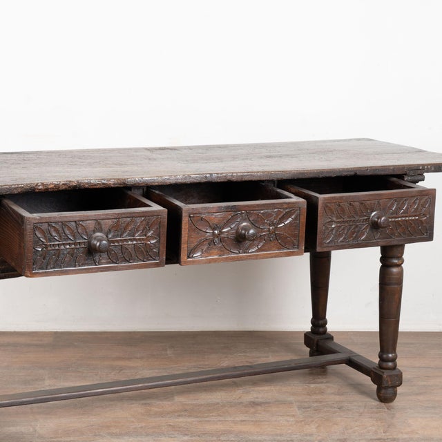 Late 18th century Spanish console table, crafted in dark oak. The table features three decorative carved drawers and is...