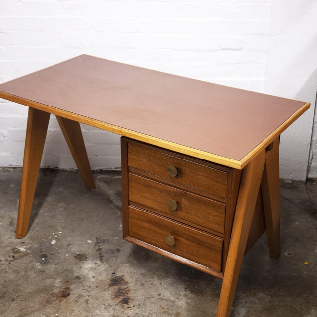 A teak and formica desk from the 1960s. The desk features chunky v taperd shaped legs. This piece is attributed to the...