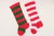 Coordinating pair of knit Christmas stockings with bold stripes and traditional red, white, and green coloration. Each is...