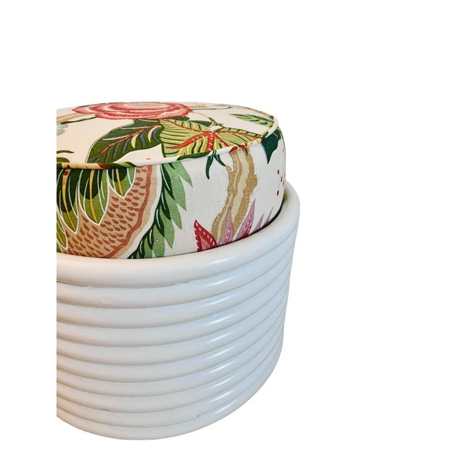 Freshly lacquered white rattan round ottoman. Reupholstered in Manuel Canovas fabric.