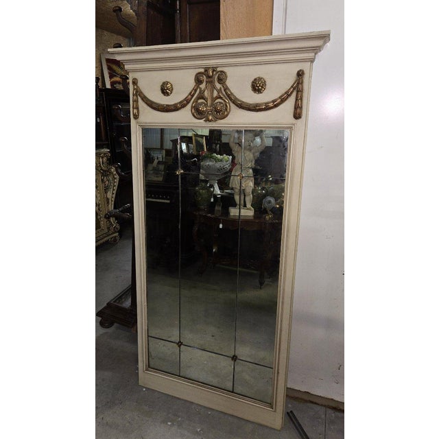 A classic-style trumeau mirror with a painted wood frame in a patinated cream tone. The upper section is richly decorated...