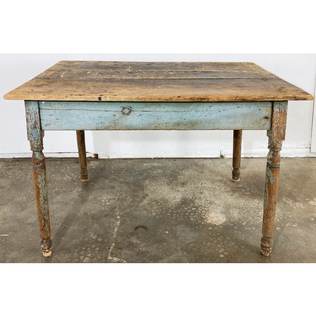 Antique primitive farmhouse table featuring weathered paint to base. Two tones of blue to aprons. Wonderful patina. Leg...