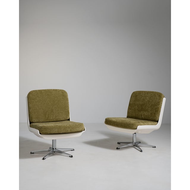 A pair of mid-century Space Age swivel chairs characterized by rounded forms and functional bases. These chairs reflect...
