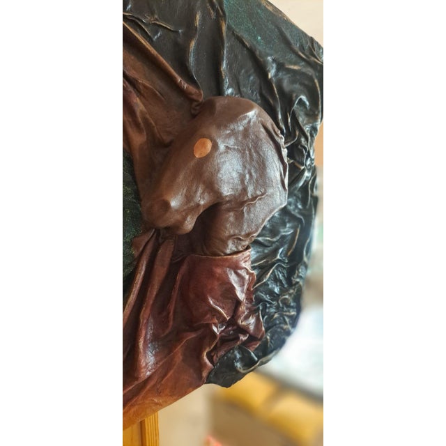 A mirror framed with various pieces of leather, each embossed by a master tanner and dyed in different colors. The...