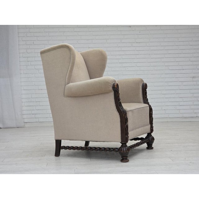 1960s, Danish wingback armchair. Original light beige furniture velour, carved oak wood, brass springs in the seat....