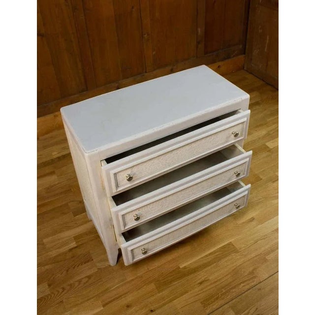 Nice vintage chest of drawers with a white patina customize with off-white wallpaper imitating crocodile skin. It opens on...