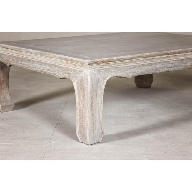 A teak wood Ming style whitewash coffee table from the 20th century with chow legs and weathered patina. This vintage teak...