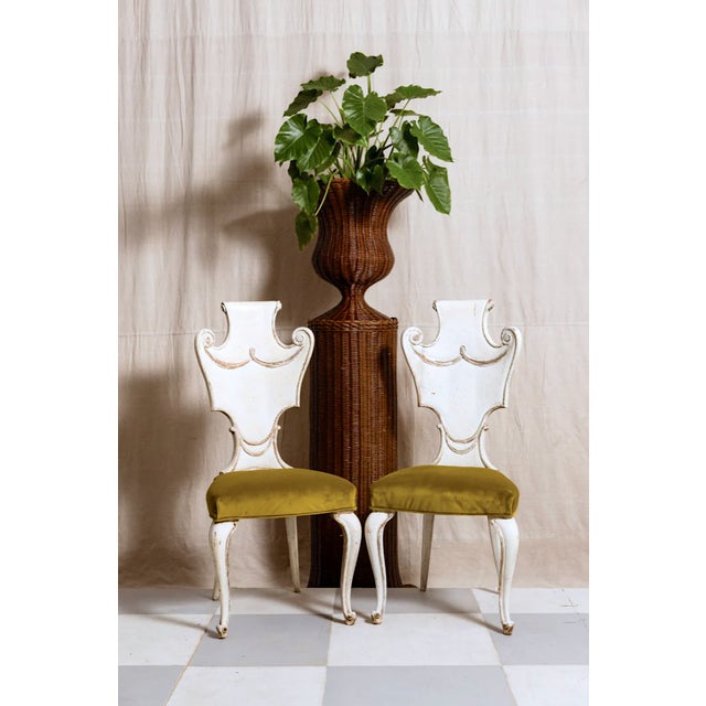 The Camille Italian Carved Chair showcases a refined off-white frame with intricately carved legs and a beautifully cut-...