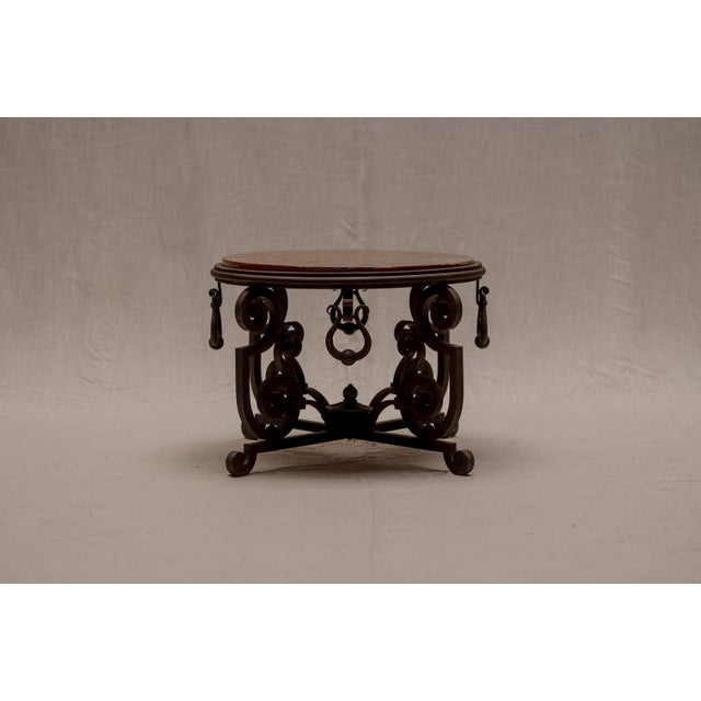 Elegant French mid-century side or coffee table featuring a striking wrought iron base paired with a richly coloured red...