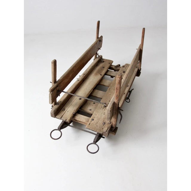 An antique wooden sled with beautifully weathered wood, a natural timeworn finish, and aged iron hardware. Its distinctive...