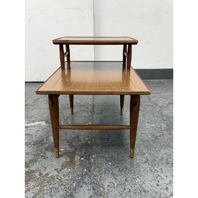 Design Plus Gallery presents a Mid-Century Modern Two-Tier Side Table. This tiered wood table has a rectangular lower...