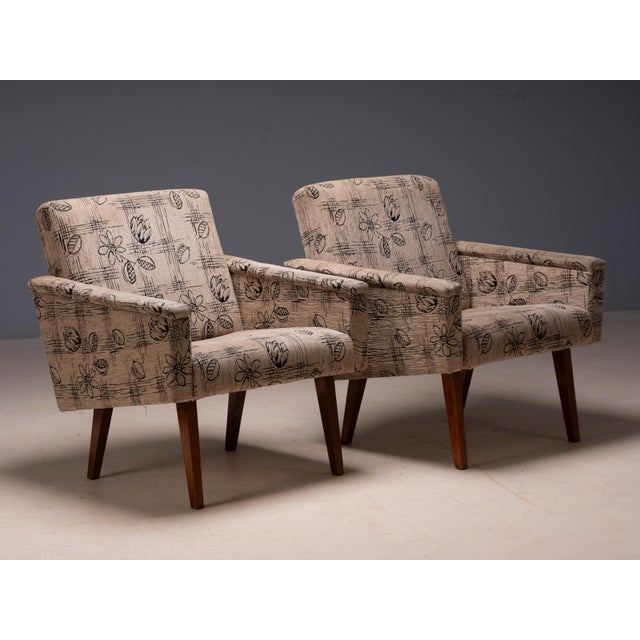A charming pair of vintage upholstered armchairs from Czechoslovakia, featuring gently angled backs, rounded armrests, and...