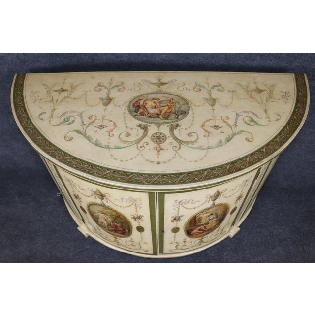 An exceptionally rare and visually breathtaking Adams-style painted demilune commode, this museum-quality piece represents...