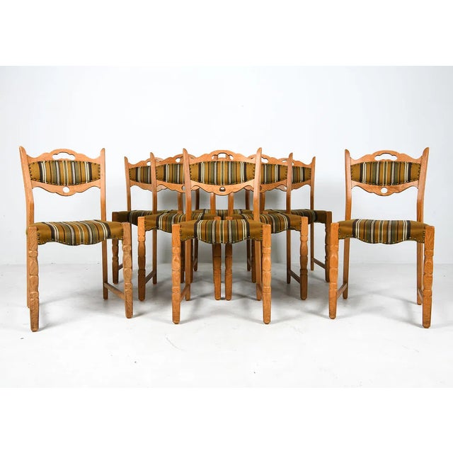 Set of eight oak dining chairs with carved trefoil cut-out backs and turned legs, each with upholstered wool seats....