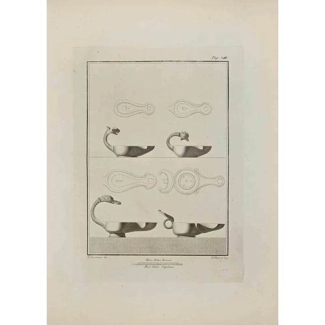 Oil Lamp with Animals Head from "Antiquities of Herculaneum" is an etching on paper realized by Giovanni Guerra in the...