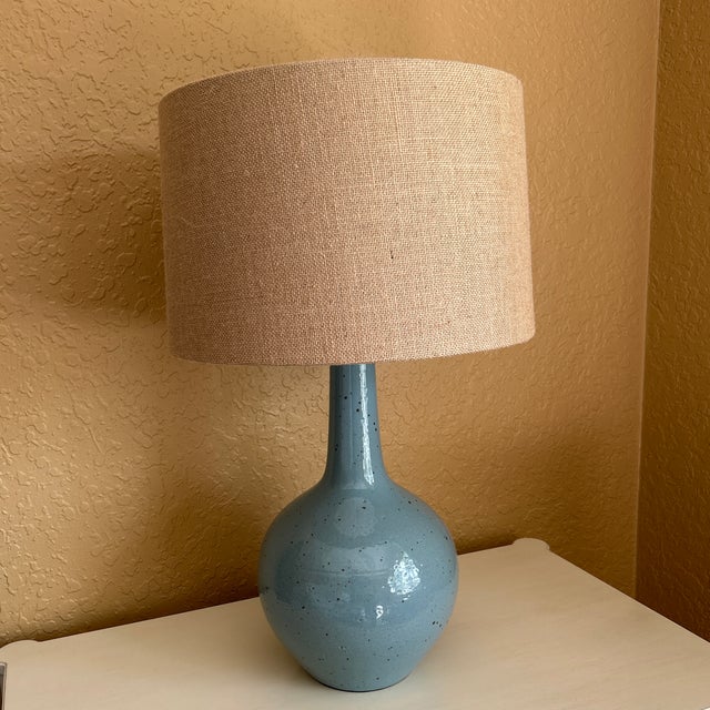 Crafted of ceramic with a fluted, smooth body and a robin's-egg finish. Natural elegance. Topped with a burlap shade and...