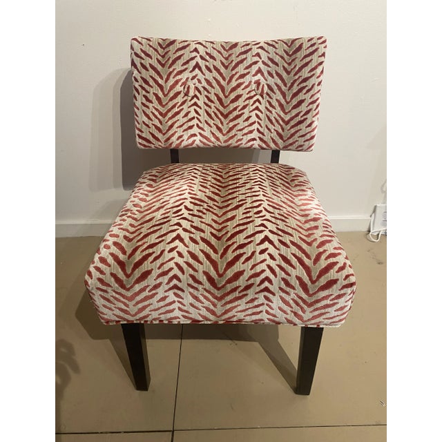 An upholstered vintage tiger print slipper chair. It has a striking red and cream pattern in velvet. This armless chair...